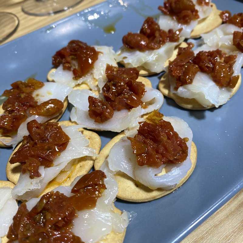 Crackers topped with salted cod and tomato