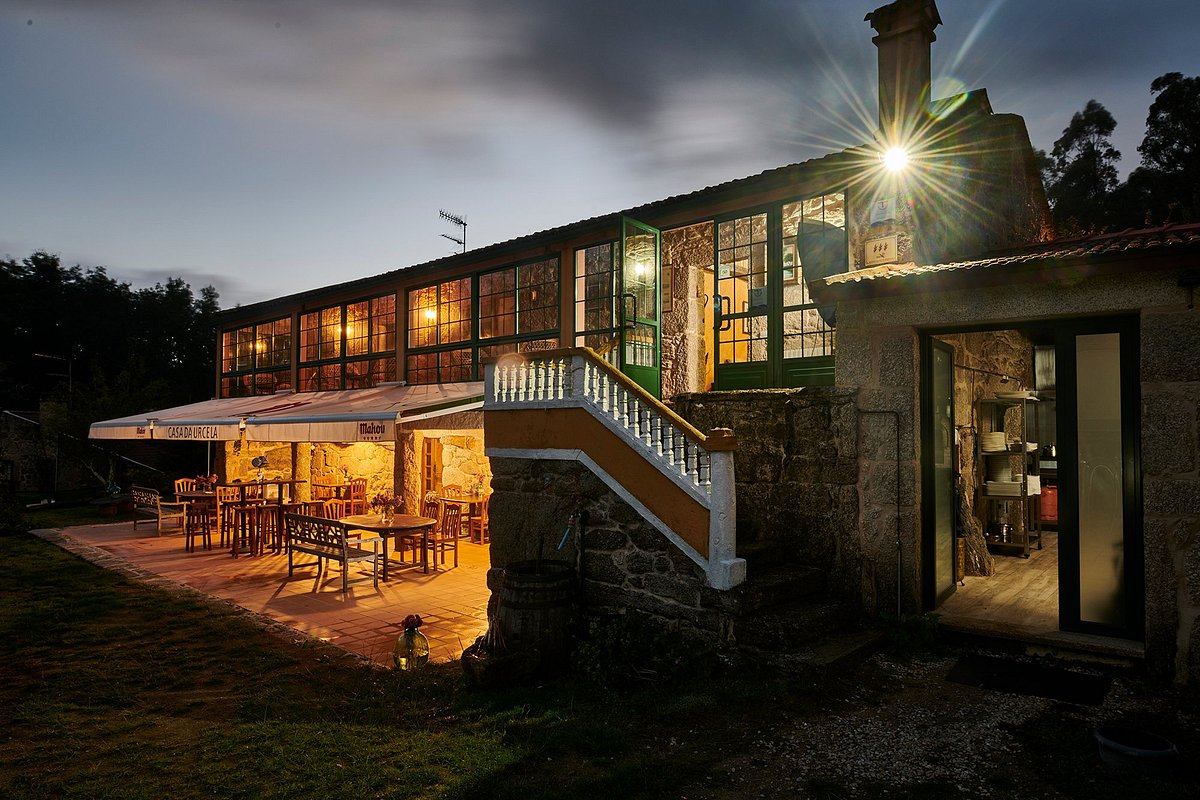 Historic Galician pazo lit up at night, with terrace and dining tables